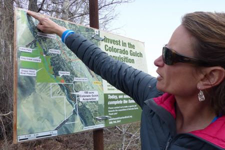 Keri York points to a Land Trust informational sign on the Hailey Greenway. Photo by Karen Bossick